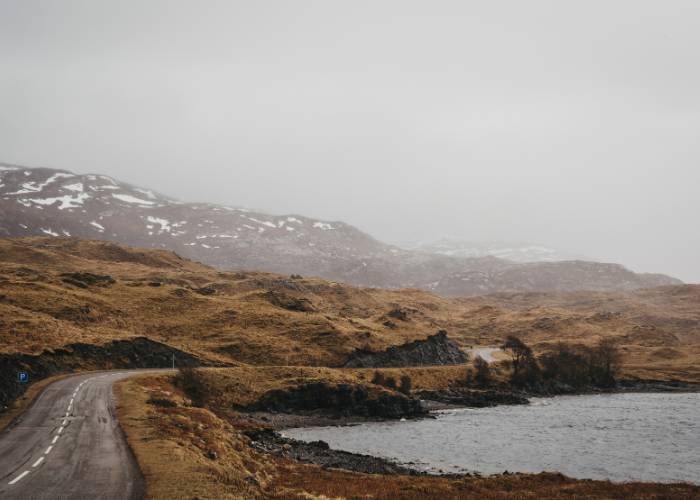 Route traversant les Highlands écossais enneigé près de Lochinver par une journée brumeuse d'hiver