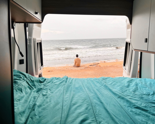 Vue depuis l'intérieur d'un van aménagé AVIS explore donnant sur un paysage au bord de mer par temps couvert