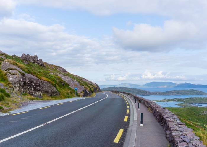 Vue panoramique de la route Ring of Kerry, serpentant à travers des paysages verdoyants, illustrant la beauté naturelle et la richesse géographique de l'Irlande