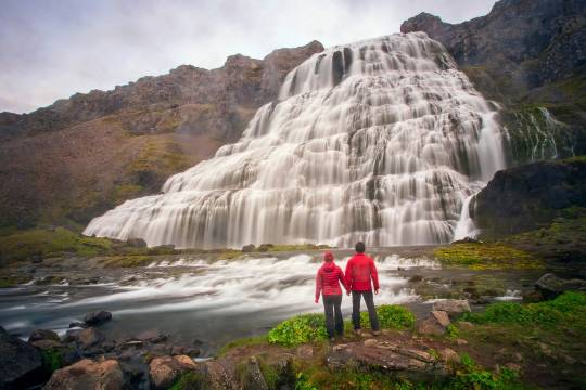 Couple devant la majestueuse cascade Dynjandi en Islande, une étape nature incontournable d’un road trip en van avec Avis Explore