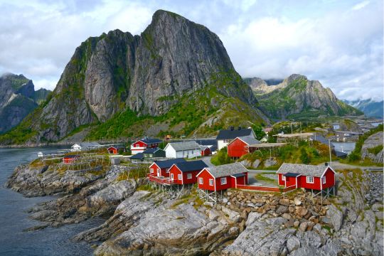 Village de Reine dans les îles Lofoten, avec ses cabanes de pêcheurs rouges face aux montagnes, étape incontournable d’un road trip en van en Laponie