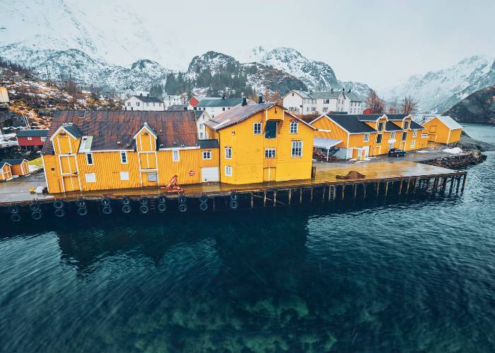 Village pittoresque de Nusfjord, classé au patrimoine mondiale de l'UNESCO,niché dans un fjord des îles Lofoten en Norvège, avec ses maisons rouges traditionnelles reflétées dans les eaux calmes, entouré de montagnes escarpées