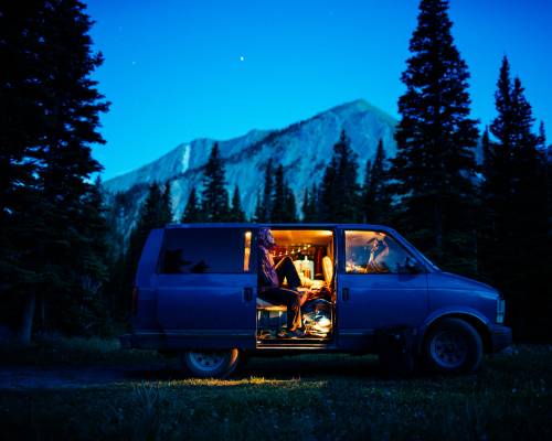 Couple dans un van en pleine nature au crépuscule, ambiance magique et montagne avec AVIS Explore