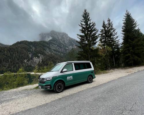 Van AVIS Explore stationné face à un lac et des montagnes, aventure nature sur les routes
