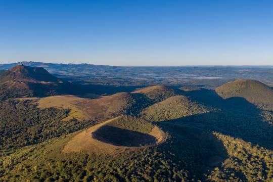 Vue aérienne des volcans de la chaîne des Puys en Auvergne avec le puy de Dôme en arrière-plan, une étape nature et ressourçante pour un road trip en van en France.