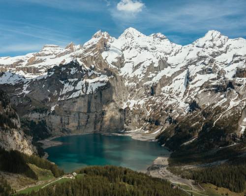 Vue du lac Oeschinen en Suisse, un lac alpin situé dans les montagnes suisses près de Kandersteg, entouré de sommets enneigés et de forêts verdoyantes.