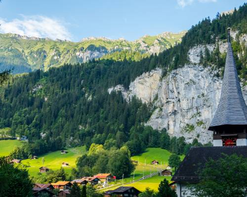 Vue panoramique de la vallée de Lauterbrunnen dans les Alpes bernoises en Suisse. La vallée verdoyante est encadrée par des falaises abruptes et des sommets enneigés